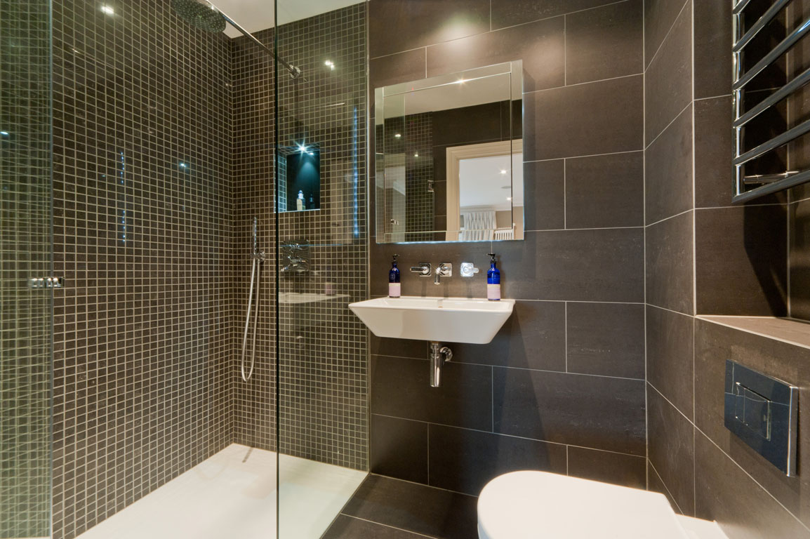 lichte inrichting van een badkamer met een douche in donkere kleuren