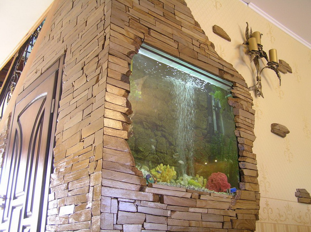 Prieškambario sienoje esantis akvariumas, išklotas akmeniu