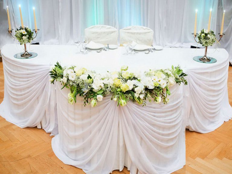 طاولة زفاف مع نسيج تزيين أبيض وشمعدانات