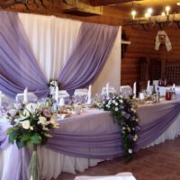 Baltų rožių puokštės vestuvių stalo kampuose