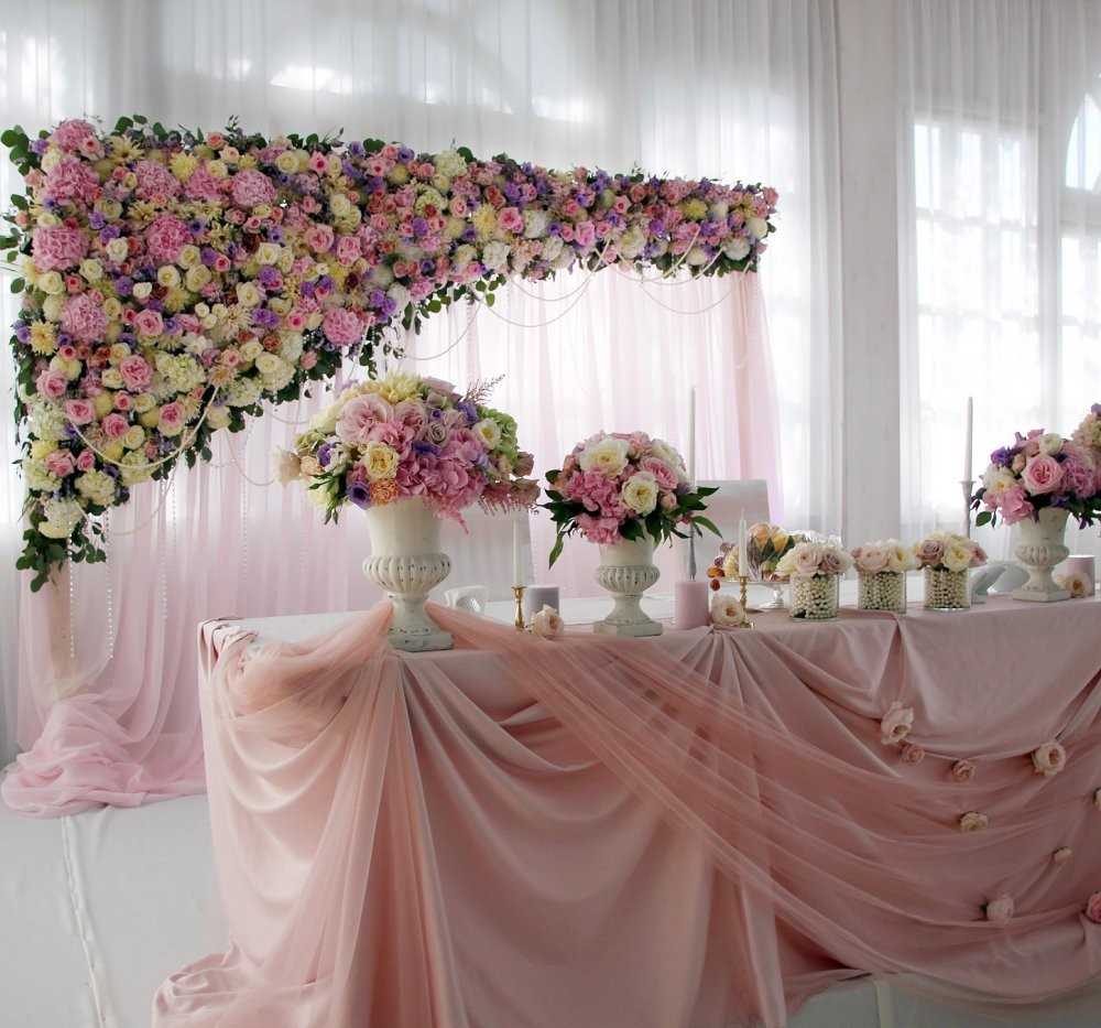 Dekoracija vjenčanog stola svijetlih boja i prozirne tkanine.