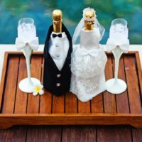 Sticle de șampanie de nuntă pe o tavă de lemn