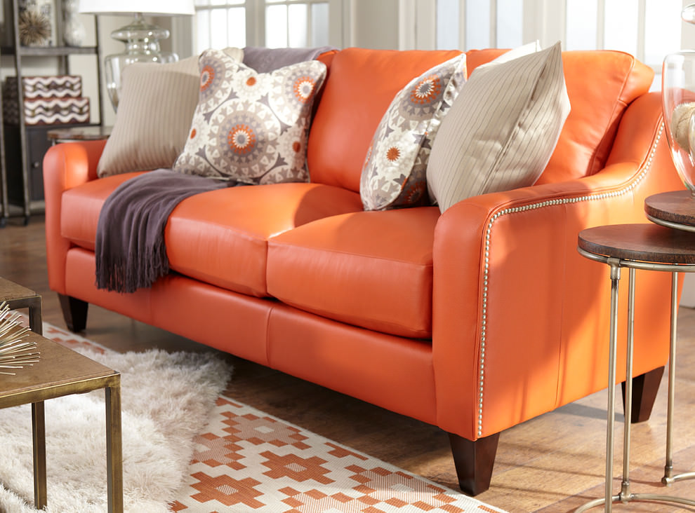 Oranžinė odinė sofa svečių kambario interjere