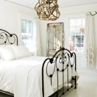 Zwart smeedijzeren bed in een witte slaapkamer