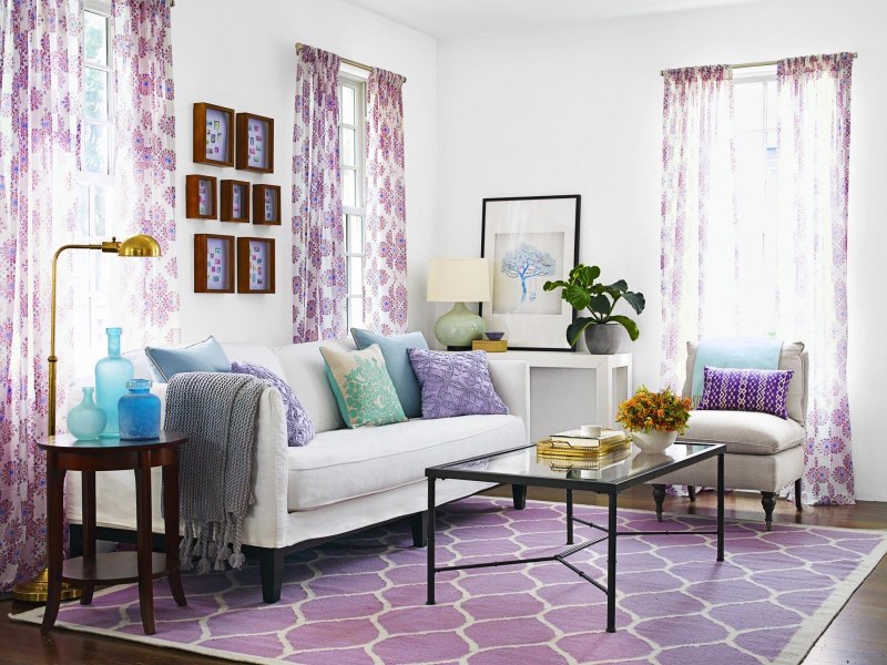 Balta sofa gyvenamajame kambaryje su levandų tekstilės medžiagomis