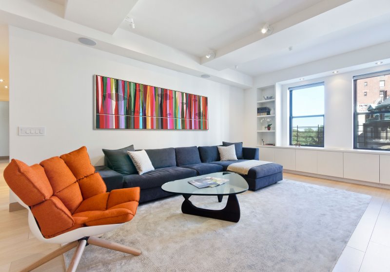 Balto gyvenamojo kambario su oranžiniu foteliu interjere dizainas