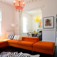 Minkšti baldai su oranžinėmis pagalvėmis svetainės interjere
