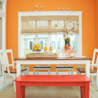 Světlý jídelní prostor s jasně oranžovou stěnou