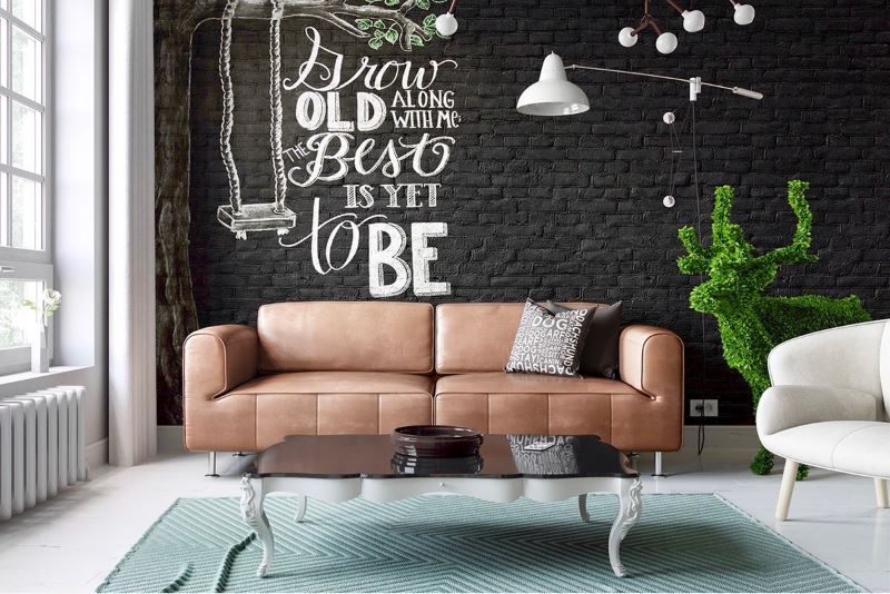 Ruda sofa prie juodos sienos su plytų mūro tapetomis
