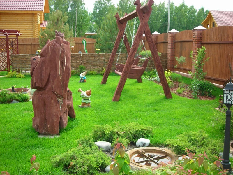 Dřevěná houpačka na zeleném trávníku soukromé zahrady