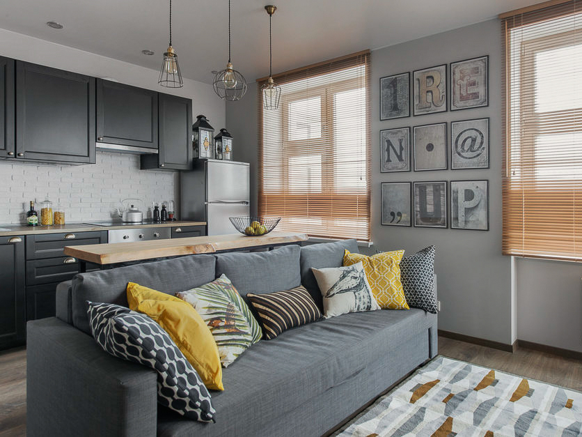 Siva sofa u kuhinji-dnevnoj sobi u pastelnim bojama