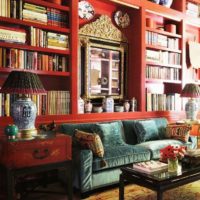 Raudonos knygų lentynos gyvenamajame kambaryje virš sofos