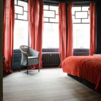 Червени завеси в сивата спалня