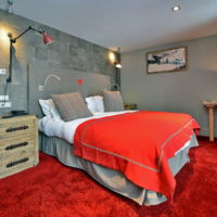 Pelēkas sienas un sarkana grīda guļamistabā