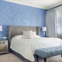 Zilas tapetes ar ziediem uz guļamistabas sienas