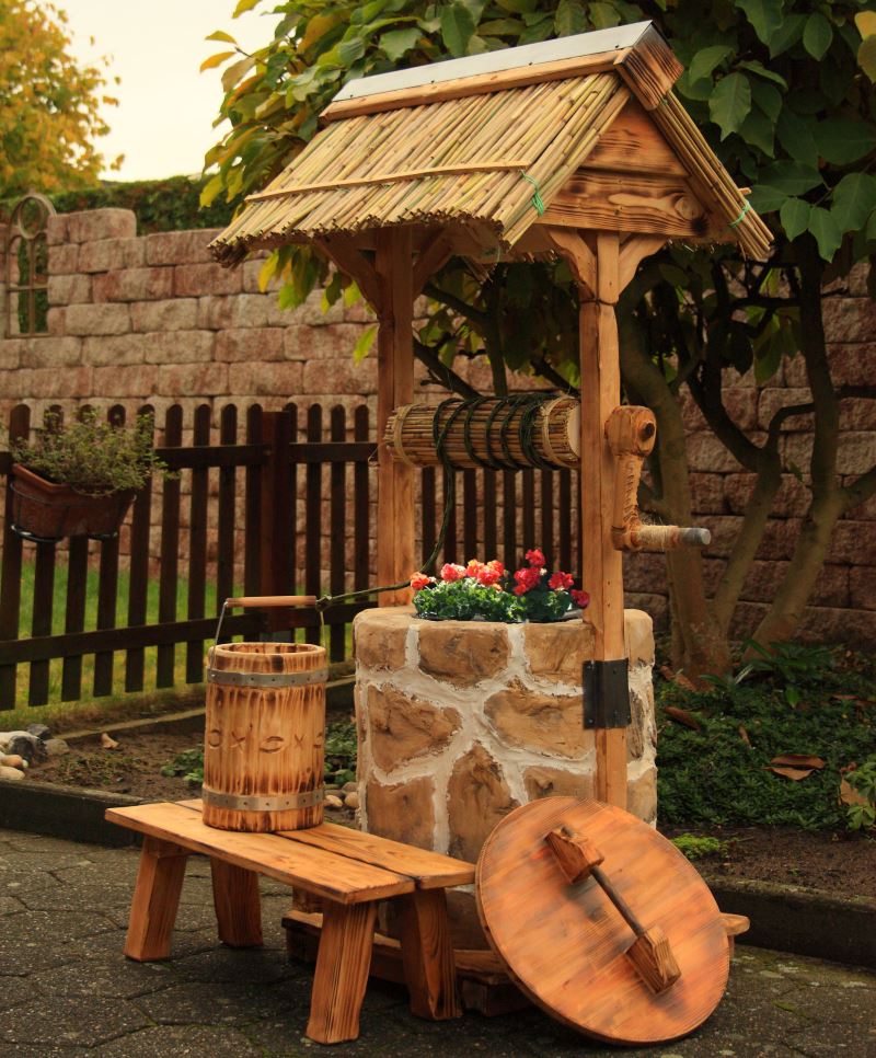 A kert kis építészeti formája kőből és fából készült dekoratív kút formájában