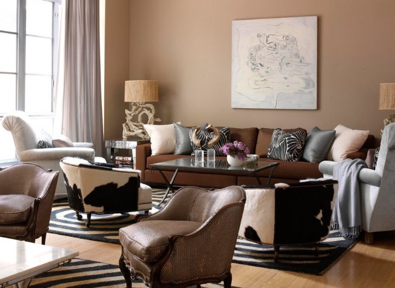 Brūns dīvāns ar auduma apdari viesistabā ar smilškrāsas sienām