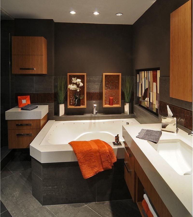 Oranžinis rankšluostis ant vonios krašto tamsiai rudame kambaryje