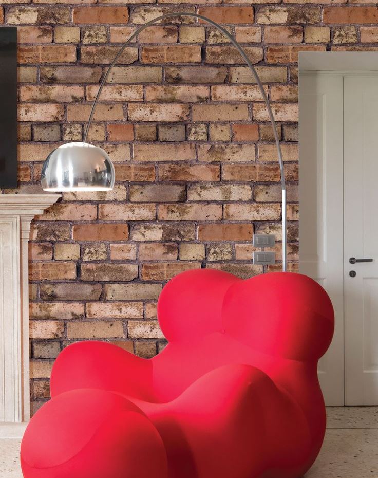 Išgalvotas raudonas fotelis prie plytų sienos