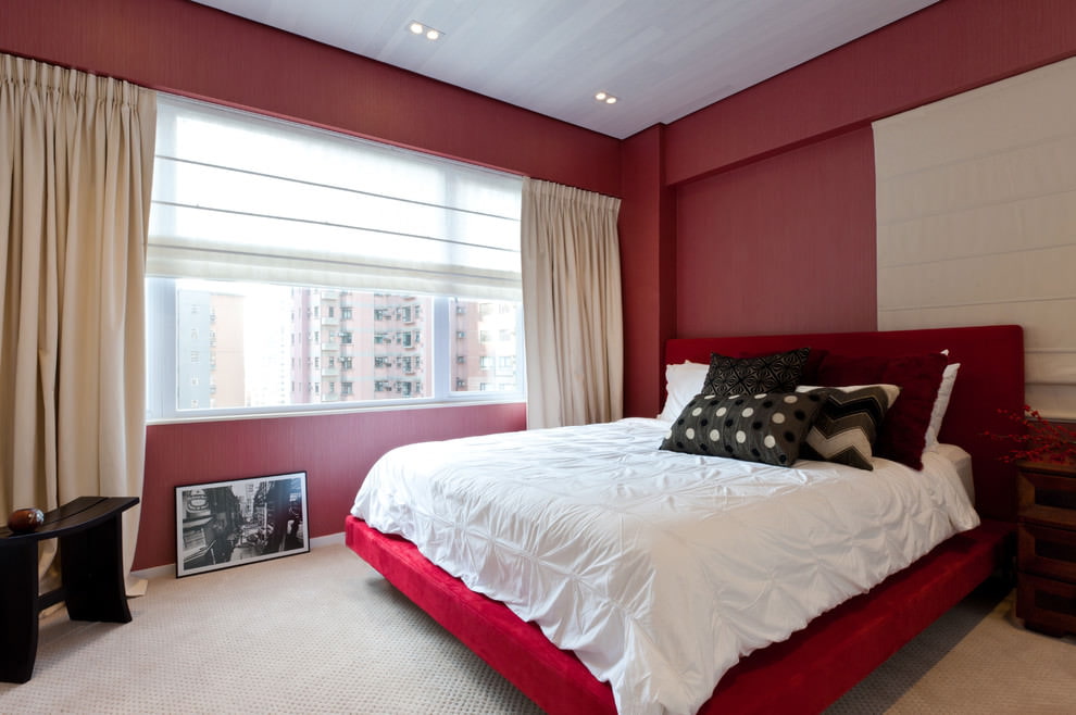 Minimalistinis miegamojo interjeras su raudonomis sienomis.