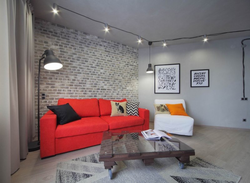 Raudona sofa pilkos palėpės stiliaus interjere