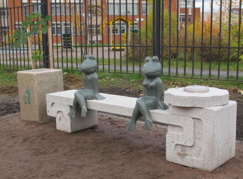 Postavy žáby sedící na dekorativní lavičce