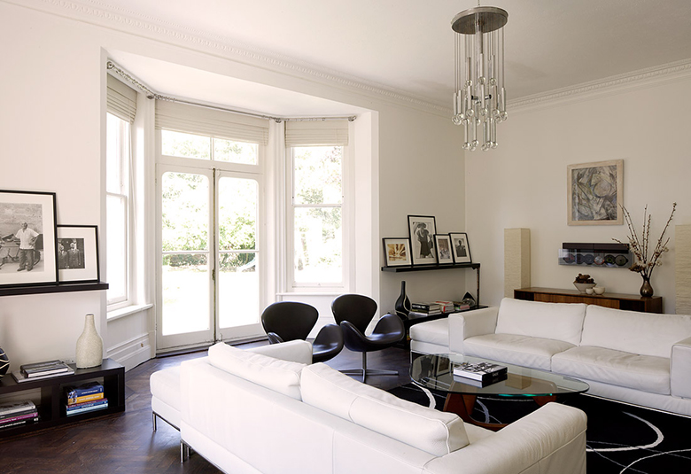 Skaistas viesistabas interjers baltā krāsā ar logiem uz grīdu