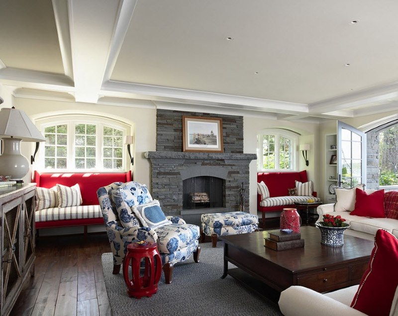 De combinatie van rode, witte en blauwe tinten in het interieur van de woonkamer met een grijze open haard