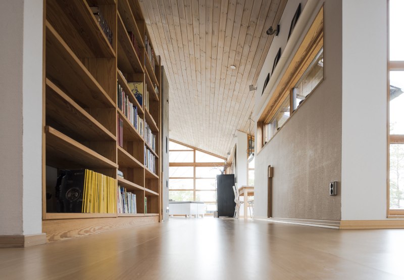 Rak buku yang diperbuat daripada kayu semula jadi di koridor sebuah rumah persendirian