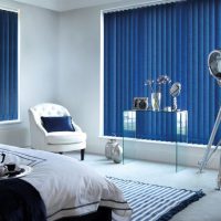 Zilas žalūzijas pilsētas dzīvokļa guļamistabā