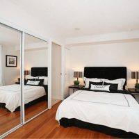 Spoguļa siena guļamistabā ar baltu gultu