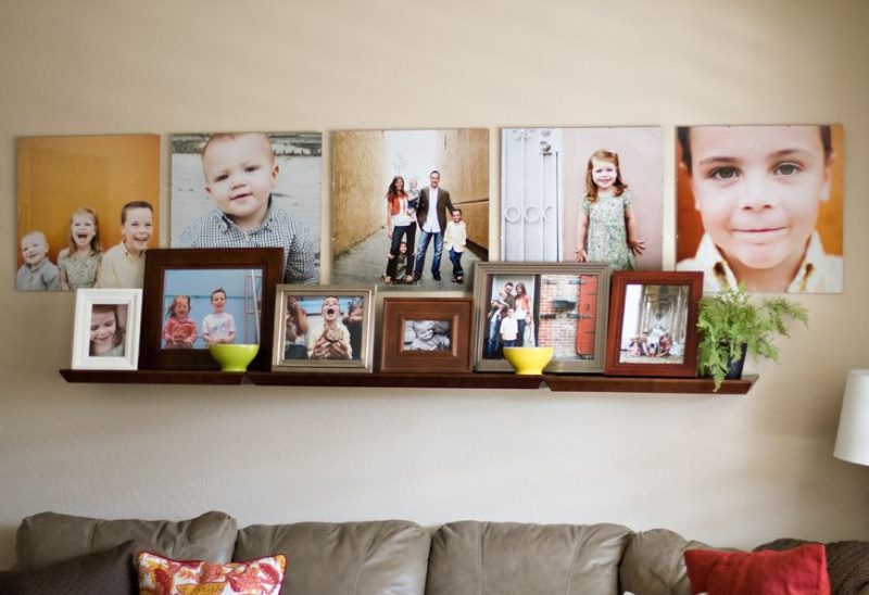 Plaukts ar ģimenes fotogrāfijām uz viesistabas sienas