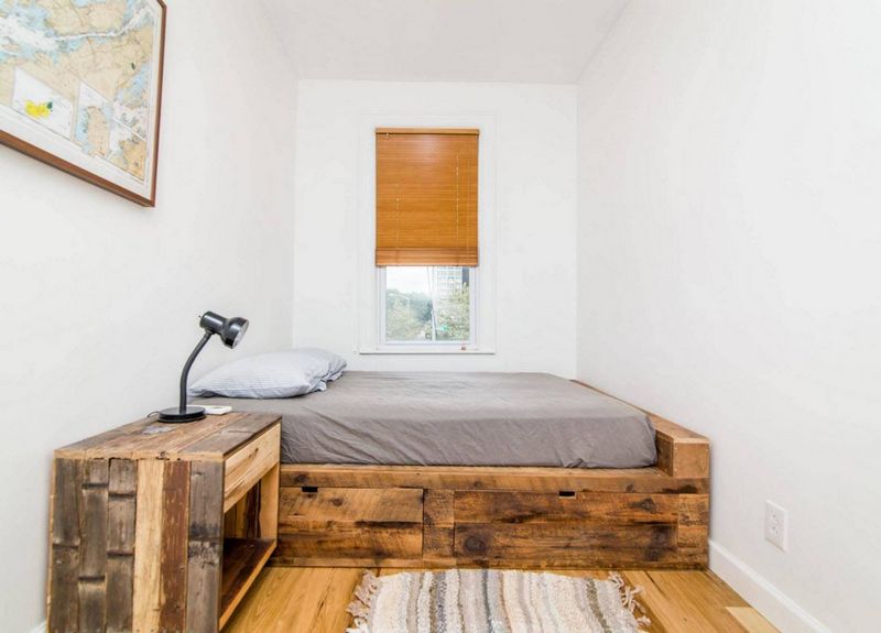 Bed op een houten podium in een smalle slaapkamer