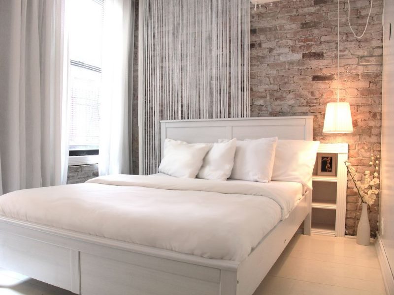Katil putih di dalam bilik tidur dengan dinding bata