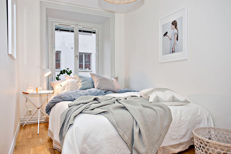 Wit tweepersoonsbed in het interieur van een smalle slaapkamer
