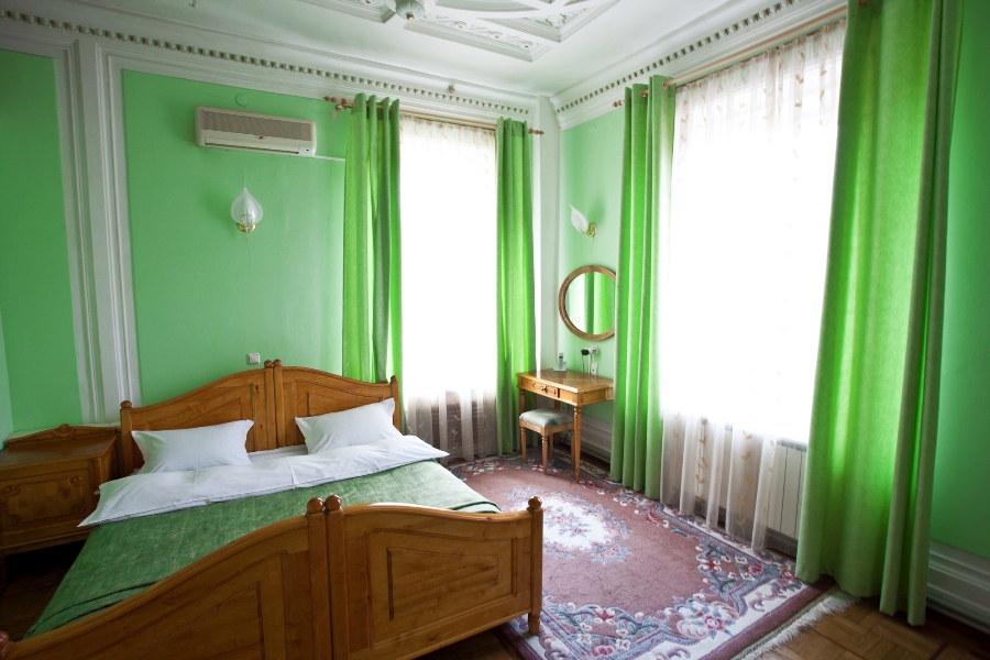 Zelené stěny a záclony v interiéru ložnice pro dospělé