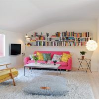 Krāsaini spilveni uz rozā dīvāna