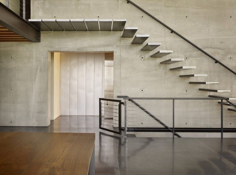 Pelēkas betona kāpnes industriālā interjerā