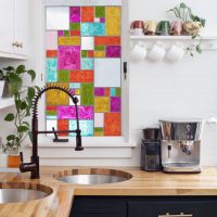 نافذة صغيرة مع نوافذ زجاجية ملونة فوق مغسلة المطبخ