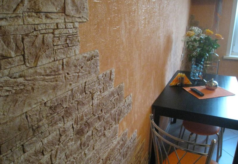 Uz ēdamistabas zonas sienas ir taupes dekoratīvā akmens flīzes