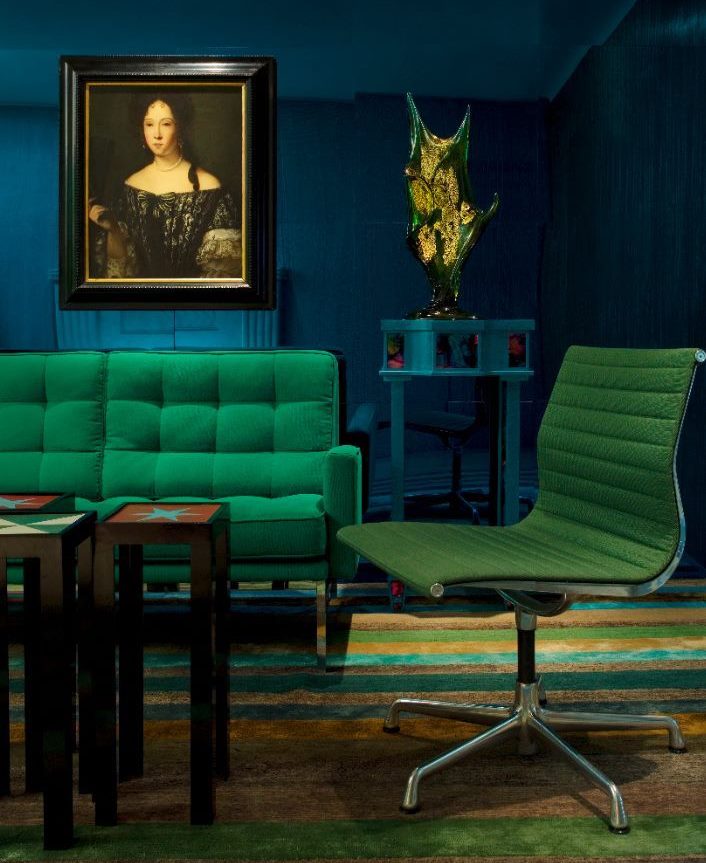 Perabot hijau melawan dinding biru gelap ruang tamu