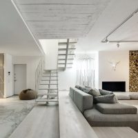 Pilka sofa šviesiame gyvenamajame kambaryje