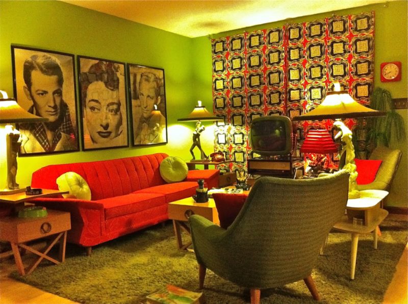 Sarkans dīvāns un portreti viesistabā ir kiča stilā