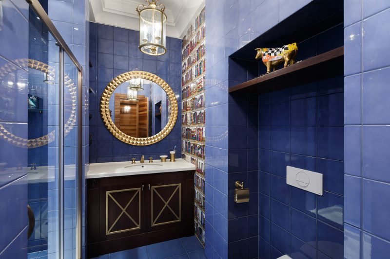 Interiér koupelny s modrými dlaždicemi na zdi.