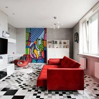 Sarkans dīvāns viesistabas dzīvokļa paneļu mājā